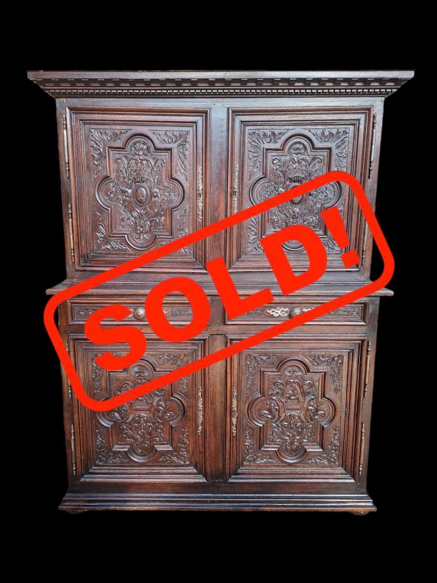 A solid oak 4-door cabinet with richly carved panels.